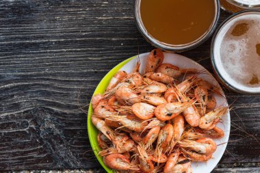 Ahşap zemin üzerinde beyaz bir tabakta taze bira ve fotokopi alanı olan taze karides pişirdim. Sağlıklı deniz ürünleri ve tatil kavramı.