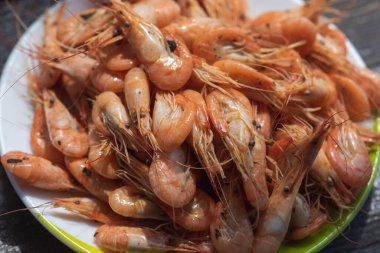 Ahşap zemin üzerinde beyaz bir tabakta taze karides pişirilmiş. Fotokopi alanı olan bir masa. Sağlıklı deniz ürünleri besin konsepti