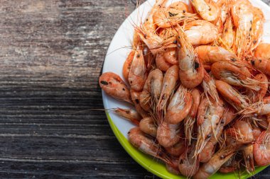 Ahşap zemin üzerinde beyaz bir tabakta taze karides pişirilmiş. Fotokopi alanı olan bir masa. Sağlıklı deniz ürünleri besin konsepti