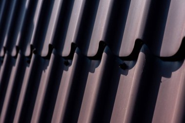 Çatı vidası kahverengi. Bükülmüş tahta vidası kahverengi bir çarşafa vidalanmış. Yakın görüş, inşaat malzemeleri, inşaat