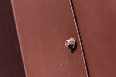 Çatı vidası kahverengi. Bükülmüş tahta vidası kahverengi bir çarşafa vidalanmış. Yakın görüş, inşaat malzemeleri, inşaat