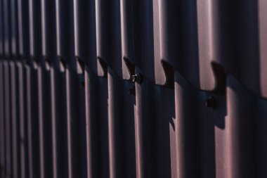 Çatı vidası kahverengi. Bükülmüş tahta vidası kahverengi bir çarşafa vidalanmış. Yakın görüş, inşaat malzemeleri, inşaat
