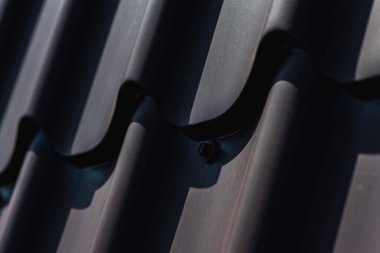 Çatı vidası kahverengi. Bükülmüş tahta vidası kahverengi bir çarşafa vidalanmış. Yakın görüş, inşaat malzemeleri, inşaat