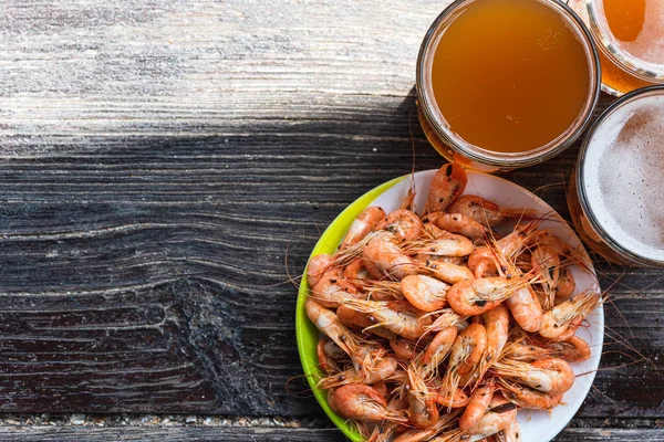 Ahşap zemin üzerinde beyaz bir tabakta taze bira ve fotokopi alanı olan taze karides pişirdim. Sağlıklı deniz ürünleri ve tatil kavramı.