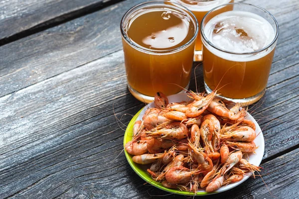 Ahşap zemin üzerinde beyaz bir tabakta taze bira ve fotokopi alanı olan taze karides pişirdim. Sağlıklı deniz ürünleri ve tatil kavramı.
