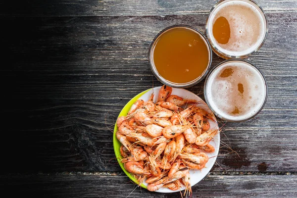 Ahşap zemin üzerinde beyaz bir tabakta taze bira ve fotokopi alanı olan taze karides pişirdim. Sağlıklı deniz ürünleri ve tatil kavramı.