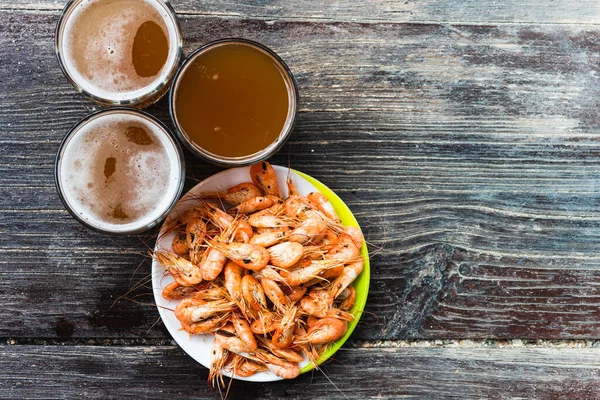 Ahşap zemin üzerinde beyaz bir tabakta taze bira ve fotokopi alanı olan taze karides pişirdim. Sağlıklı deniz ürünleri ve tatil kavramı.