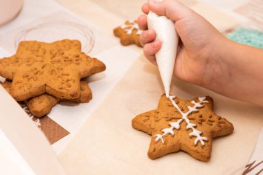 Üst manzara, renkli Paskalya objeleri, fırın, masada ve ellerde duran kurabiyeler boyalı, küçük, süslü kurabiyeler. Çocuklar anneler için zencefilli kurabiye süslüyor. Mutlu anneler günleri.