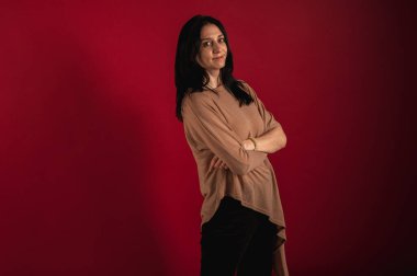 Güzel, meraklı, neşeli bir esmerin portresi. Çok fazla düşünen, gözlerini kaçıran, parlak kırmızı bir arka planda soyutlanmış.