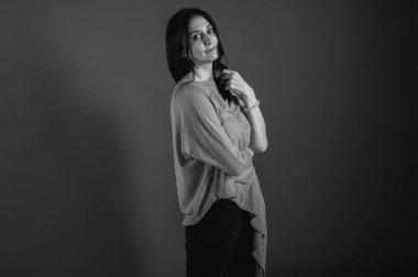 Güzel, duygusal, güzel, neşeli bir kızın siyah beyaz portresi. Düz, gri arka planda soyutlanmış görünüyor..