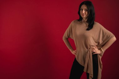 Çok düşünen, düzgün görünen, parlak kırmızı bir arka planda izole edilmiş güzel, duygusal, güzel, ilginç ve neşeli bir esmerin portresi..