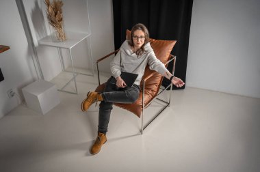 Genç, güzel, duygusal olarak şaşırmış, gözlüklü, parlak bir odada sandalyede oturan bir iş kadınının portresi. Yazı için yerler