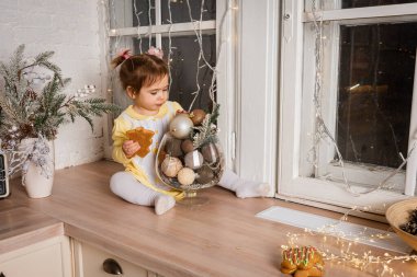 Küçük bir kız, şehirdeki bir kafede, mutfakta kahvaltı yapıyor. Çocuk zencefilli ekmek yiyor. Restorandaki parlak kahvaltı masası, eko kağıt poşet. Çocuk zencefilli çörek yiyor. 