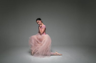 Genç, güzel, narin, güzel balerin. Uzun soluk pembe bir elbiseyle dans ediyor. Üniformalı bir arka planı var. Bale, dans, dansçı. Yazı için yer