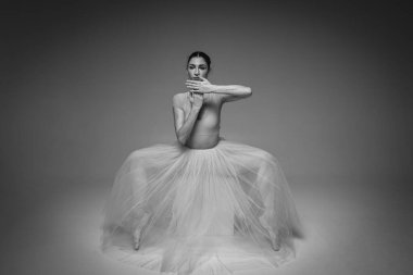 Klasik siyah-beyaz portre, genç, güzel, kırılgan, güzel balerin uzun soluk pembe bir elbiseyle dans ediyor, arka planda tüller var, el hareketleri, kısıtlı ton. Bale, dans, dansçı. Yazı için yer