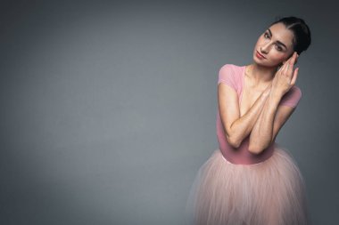 Güzel, narin, güzel bir balerinin portresi. Uzun, soluk pembe bir elbise içinde. Üniformalı bir arka planı var. Bale, dans, dansçı.
