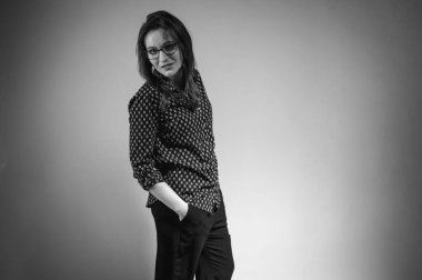 Koyu renk pantolonlu, gömlekli, duygusal, gülümseyen bir kadın. Örgü gömlekli çekici kız sarı arka planda dans ediyor. Genç bir kızın portresi. Yazı için yer