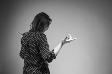 Siyah beyaz fotoğraf. Sıradan mavi gömlekli bir kızın arka görünüşü el hareketleri, reklamcı bir iş kadını, saç estetiği, şampuan gösteriyor. Sarı arka planda kapalı stüdyo çekimleri