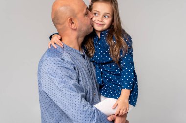 Babası küçük kızını kollarında tutuyor, eğleniyor, gülüyor, hafif bir arka planda, ebeveyn sevgisiyle. - Aile. Seçici odak 
