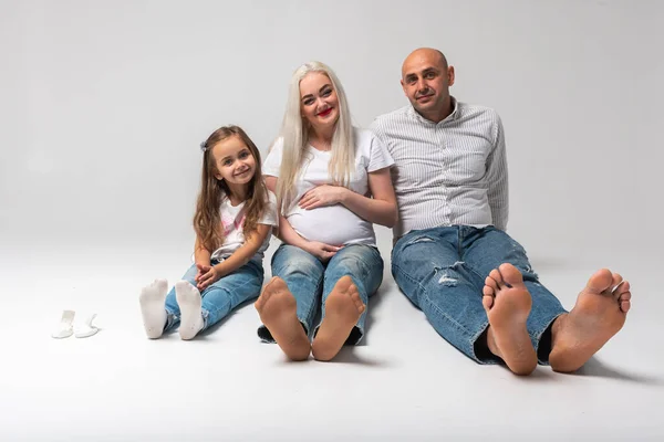 Üç kişilik mutlu bir aile yerde oturuyor. Anne, baba ve küçük çocuk. Annem hamile. Haberler iyi, hamile, ayaklarımız çıplak.