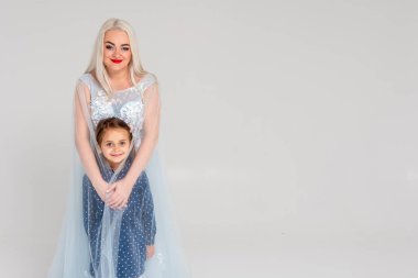 Güzel, genç hamile bir kadın ve küçük kızı, açık bir arkaplanda. Mutlu aile kavramı