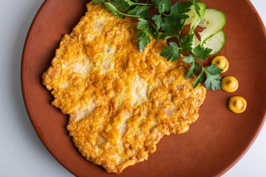 Kızarmış domuz pirzolası ve yeşil maydanoz. Beyaz arka planda kahverengi kilden bir tabakta.