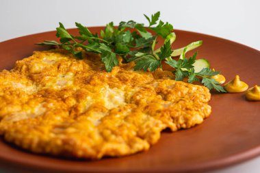 Kızarmış domuz pirzolası ve yeşil maydanoz. Beyaz arka planda kahverengi kilden bir tabakta.