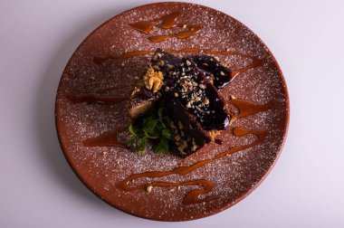 Fındıklı krep çikolatalı pasta, beyaz arka planda izole edilmiş kahverengi kil tabakta ballı kek. Yüksek kalite fotoğraf