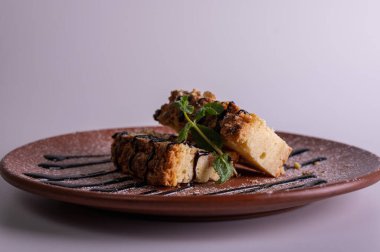 Beyaz arka planda kahverengi kil tabakta yaban mersini soslu bir parça cheesecake. Yakın çekim görüntüsü. Çay için tatlı konsepti