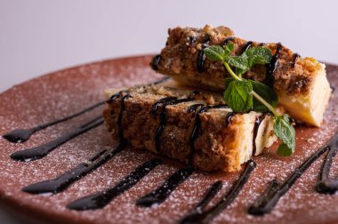 Beyaz arka planda kahverengi kil tabakta yaban mersini soslu bir parça cheesecake. Yakın çekim görüntüsü. Çay için tatlı konsepti