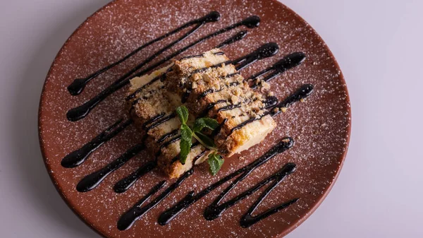 Beyaz arka planda kahverengi kil tabakta yaban mersini soslu bir parça cheesecake. Yakın çekim görüntüsü. Çay için tatlı konsepti