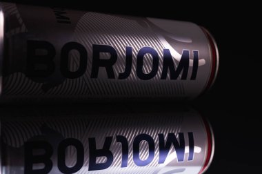 Ukrayna, Lviv, 7 Nisan 2022, yakın çekim, metal bir kavanozda soğuk içecek BORZHOMI, yalan söylüyor, ayna görüntüsü, siyah bir arka planda izole edilmiş, reklam için, tahtalar. Alçak tuş