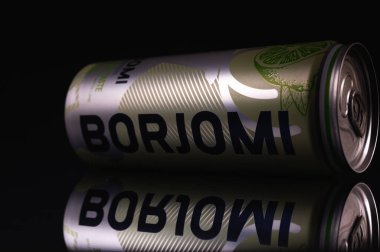 Ukrayna, Lviv, 7 Nisan 2022, yakın çekim, metal bir kavanozda soğuk içecek BORZHOMI, yalan söylüyor, ayna görüntüsü, siyah bir arka planda izole edilmiş, reklam için, tahtalar. Alçak tuş