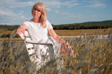 Genç bir kız sonsuz lavanta tarlasının ortasında bir bankta oturuyor. Gündüz çekilmiş bir portre resmi.