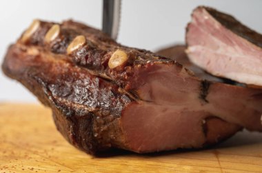 smoked, dried, homemade meat ribs on a wooden board, sliced on a light background