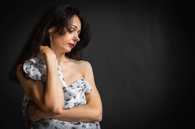 Zarif, güzel, duygusal, seksi bir kadının yakın plan portresi, açık büyük bir şapkanın arkasına saklanıyor. Koyu gri arka planda gevşek saçlı güzel bir fotoğraf modeli.