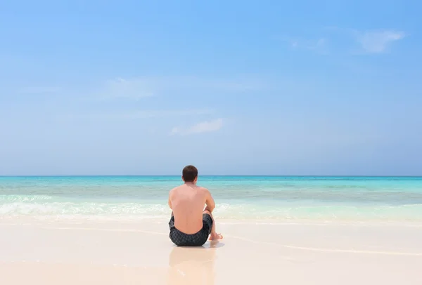 Man sitting lonely on beach — Stock Photo, Image