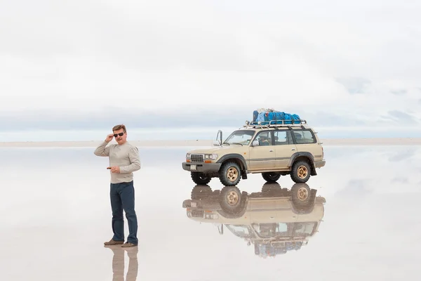 Hombre y coche en el lago Salar de Uyuni, Bolivia — Foto de Stock