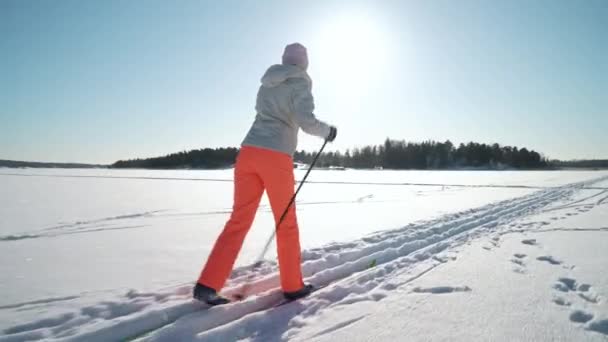 Soğuk ve güneşli bir günde Finlandiya 'da donmuş bir körfezde kayak yapmaya giden bir kadın. — Stok video