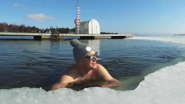 Мужчина мечтает о отпуске, плавающем на надувном фламинго в ледяной яме — стоковое видео