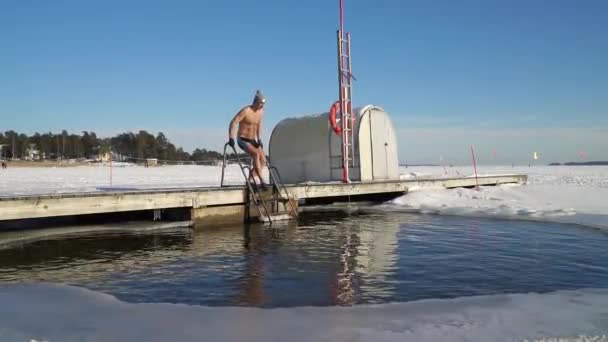 Человек, плывущий зимой в ледяной яме. — стоковое видео