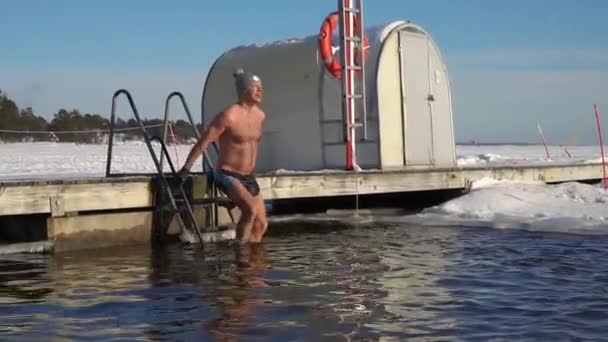 Een man zwemt in een ijsgat in de winter.. — Stockvideo