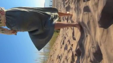 Sahilde yürüyen genç bir kadının ince bacaklarının yakın çekimi.