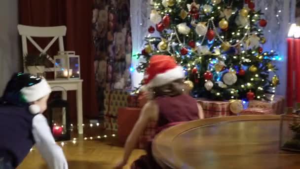 Little boy and girl running to presents under the Christmas tree — Stock Video