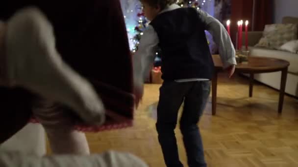 Mały chłopiec i dziewczyna biegnie do prezentów pod choinką — Wideo stockowe