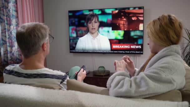 Família casal assistindo TV notícias sentado no sofá na sala de estar — Vídeo de Stock