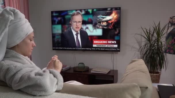 Uma jovem mulher está fazendo uma manicure Sentado no sofá na sala de estar com uma TV — Vídeo de Stock