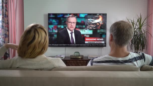Rodinný pár Sledování TV News Sedí na gauči v obývacím pokoji spolu. — Stock video