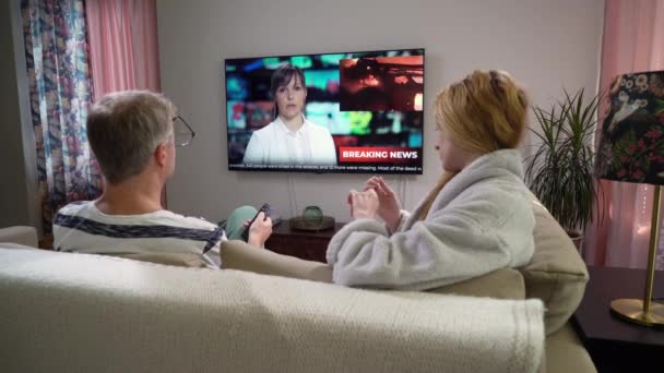 Familienpaar schaut Fernsehnachrichten auf Couch im Wohnzimmer — Stockvideo