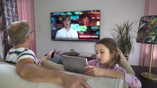 Un uomo di mezza età con la sua figlioletta davanti a uno schermo televisivo. — Video Stock